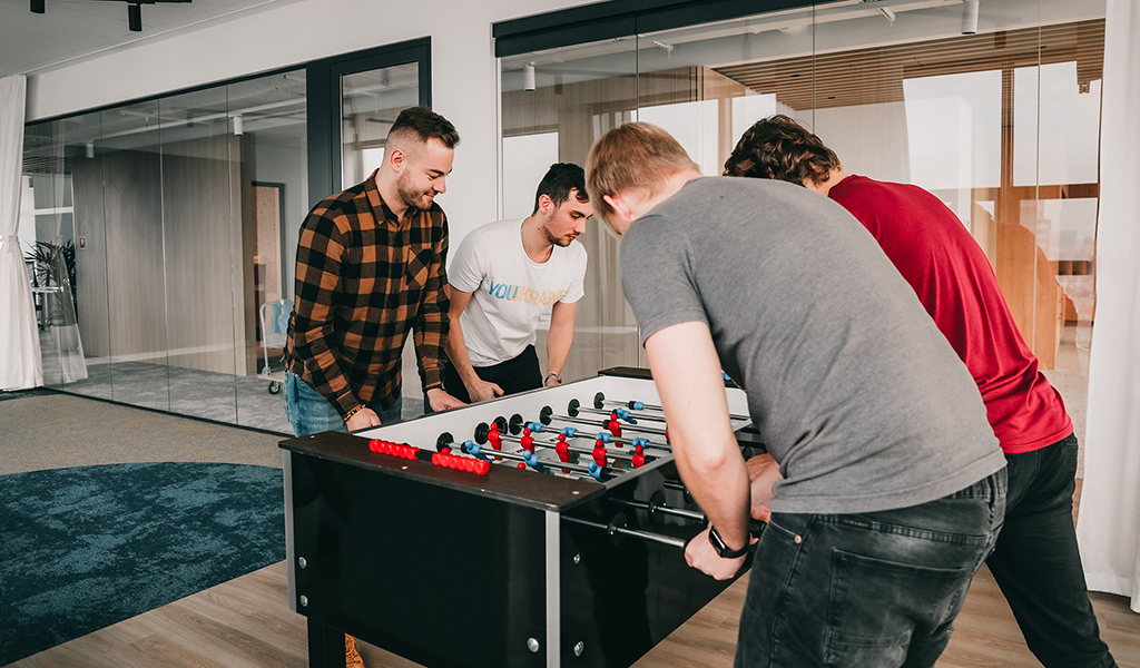 Four team members playing table football 